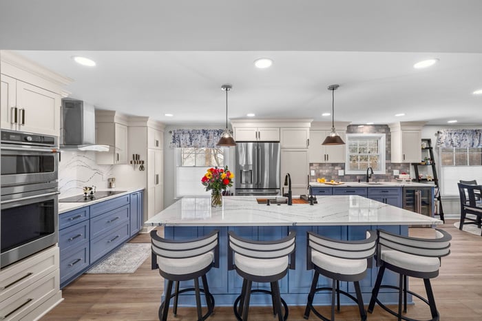 Spacious modern kitchen featuring upscale stainless steel appliances, a large central island with bar seating, sleek cabinetry, and blue accent colors in a bright, open layout.