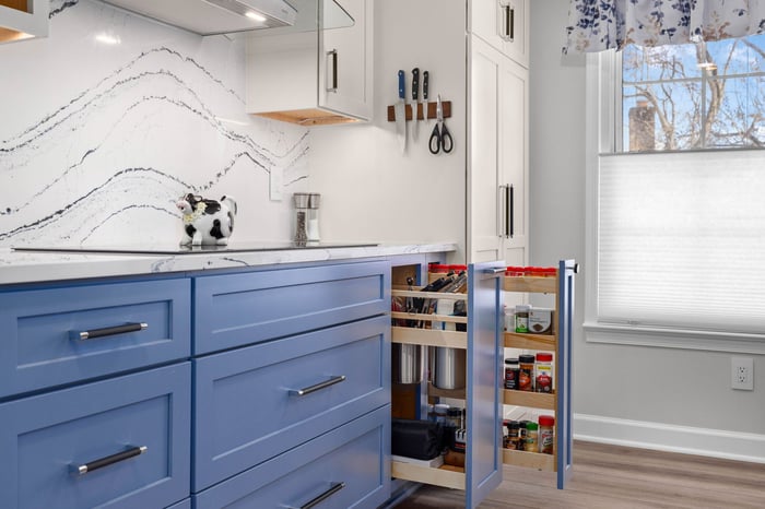 Two open blue kitchen drawers showcasing unique storage solutions, including organized compartments for utensils and neatly arranged spice rack.