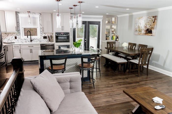 Open-concept design featuring a kitchen with a large island, a dining area with a sleek table and chairs, and a living room with comfortable seating, all in a bright, cohesive space.