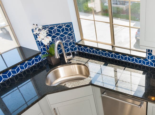 Kitchen windows that add natural light into the space over granite countertop and sink.